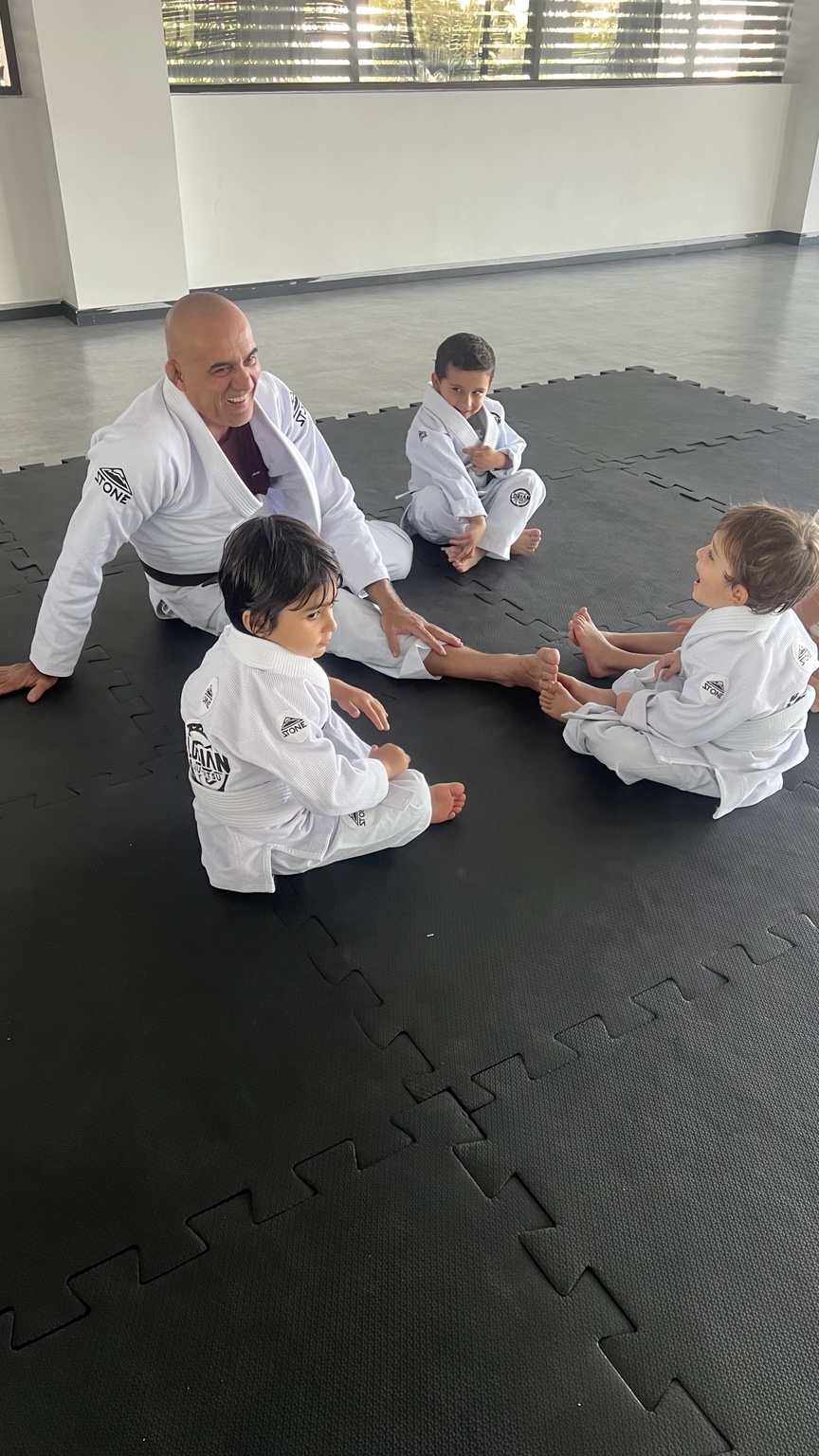 Professor Carlos orientando crianças da turma Baby no tatame